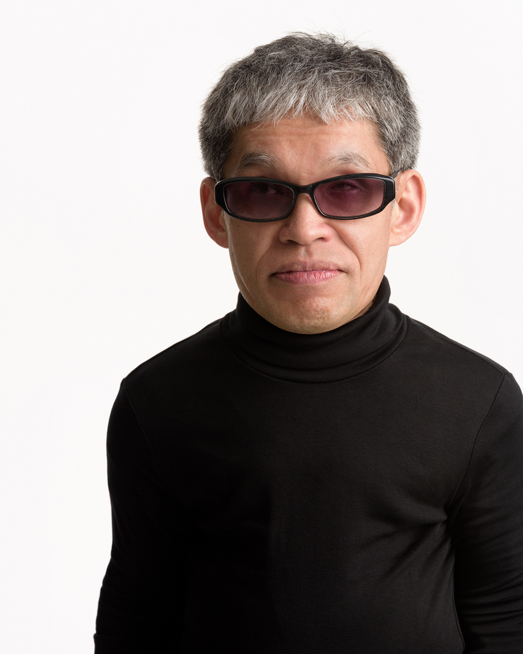 写真:髪はグレーでサングラス、タートルネック姿
